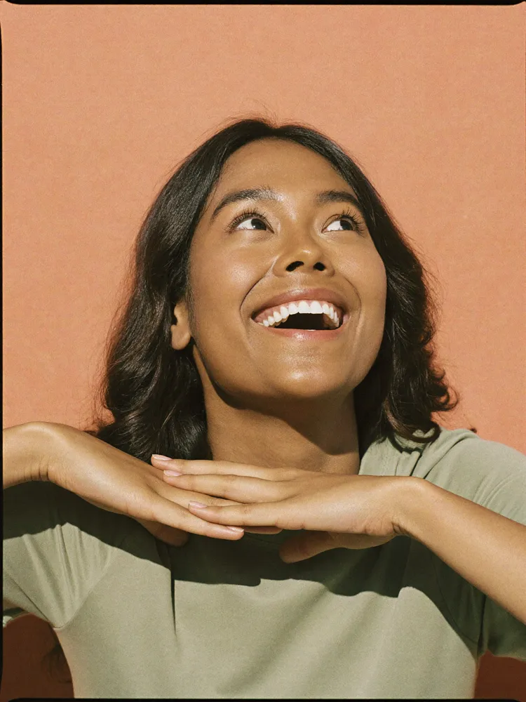 Girl looking up and smiling to showcase dental exams available at Ora